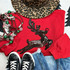LARGE Sequin Reindeer Chenille Patch, close-up of a black sequin reindeer patch on a red sweater, surrounded by Christmas decorations, jeans, and sneakers.