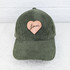 Lover Leather Hat Patch, green corduroy baseball cap with a pink heart-shaped patch embroidered with the word "Lover" in black cursive font.