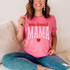 One Loved Mama DTF Heat Transfer, pink T-shirt with 'one loved MAMA' text and heart graphic, worn by a smiling woman sitting on a beige sofa.
