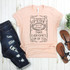I'd Rather Be Someone's Shot of Whiskey Than Everyone's Cup of Tea Sublimation Transfer T-shirt, pink casual t-shirt with black text design laid on a light wooden surface with distressed jeans, brown sandals, and a small green plant nearby.