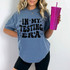 In My Testing Era DTF Heat Transfer, a woman wearing a blue T-shirt with black lettering and decorative stars, holding a pink rhinestone-studded tumbler.