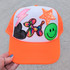 Neon Orange Sequin Star Hat/Pocket Patch, colorful embroidered patch with a lightning bolt, star, balloon dog, smiley face, and the word 'LOVE' on an orange baseball cap.