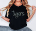 Tigers Sequin Patch, close-up of a woman wearing a black T-shirts with the word 'tigers' in colorful sequins, accessorized with rings, necklace, and bracelet.