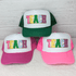 TEACH Chenille & Glitter Hat/Pocket Embroidered Patch, colorful patch with the word TEACH in pink, yellow, green, blue, and purple embroidery on white foam front panels of trucker caps.