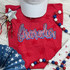 Firecracker Red and Blue Sequin Youth Patch, vibrant red T-shirt with patriotic embroidery, surrounded by festive decorations.