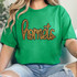 Hornets Gold Sequin Patch, a shiny gold sequined patch spelling 'hornets' in cursive script on a bright green T-shirt.