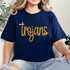 Trojans Gold Sequin Patch, gold sequined patch with the word 'Trojans' in cursive on a navy blue t-shirt.