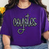 Coyotes Sequin Patch, a sparkling rhinestone embellishment in the shape of the word 'Coyotes' with a cross integrated into the design, on a purple t-shirt.
