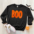 Orange BOO Sequin Patch, orange sequin applique with the word BOO on a black sweatshirt.