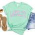 Lake Life Varsity Style DTF Heat Transfer, mint green T-shirt with pink and blue text, casual fashion flat lay with denim shorts, sunglasses, and sandals