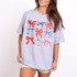 Coquette Bows DTF Heat Transfer, colorful bows design on a grey T-shirt worn by a smiling woman.
