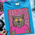 Bearcats Colorful Mascot DTF Heat Transfer, vibrant and playful illustration of a mascot with star-shaped glasses and a pink shirt on a blue t-shirt, designed for custom apparel decoration.