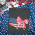 American Flag Map Coquette DTF Heat Transfer, graphic design of a map of the United States with an American flag pattern and a pink bow on a dark gray t-shirt, patriotic-themed party or celebration apparel.
