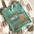 Running On A Prayer And Iced Coffee DTF Heat Transfer, humorous graphic design of a coffee cup with a straw and iced coffee inside on a mint green T-shirt.