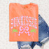 Sunkissed Coquette DTF Heat Transfer, vibrant orange t-shirt with tropical-themed design including pink lettering, green palm trees, and a pink polka-dotted bow.