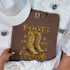 Boots On The Ground Faux Rhinestone DTF Heat Transfer, image of a brown T-shirt with a rhinestone graphic of cowboy boots and the text "Boots On The Ground".