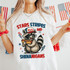 Stars Stripes And Shenanigans DTF Heat Transfer, patriotic design with raccoon holding a hot dog, American flag motifs, bright red, white, and blue colors for celebrating American holidays.