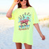 Salty Flamingo Palm Trees DTF Heat Transfer, vibrant beach-themed design featuring pink flamingos and palm trees on a neon yellow t-shirt worn by a woman at the beach.