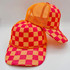 Neon Pink & Orange Checkered Foam Trucker Hat, stylish mesh front and adjustable brim with vibrant checkered pattern.