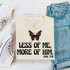 Less Of Me, More Of Him Butterfly DTF Heat Transfer, white T-shirt with butterfly graphic and biblical quote, casual jeans, sneakers, and jewelry on a white quilted surface.