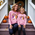 Halloween Mini Bow DTF Heat Transfer, design on pink sweatshirts for mother and daughter with Halloween theme, pumpkins in background.