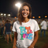 Colorful Jumping Mascot DTF Heat Transfer, vibrant multicolored cartoon mascot design on a white t-shirt worn by smiling woman at outdoor event.