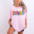 Colorful Jumping Mascot DTF Heat Transfer, vibrant multicolor letters spelling 'FLYERS' on a pink T-shirt worn by a woman with blonde wavy hair.