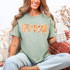 Fall Patterned Names DTF Heat Transfer, close-up of a woman wearing a T-shirt with fall-themed patterned words spelling 'Fall' in various orange, plaid, and floral patterns, perfect for seasonal customization.