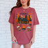 Cozy Cabin Reading Retreat DTF Heat Transfer, a graphic t-shirt featuring a cozy cabin surrounded by trees, pumpkins, a campfire, books, and autumn-themed decorations, perfect for fall reading and relaxation.