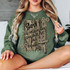 God Is Within Her Camo DTF Heat Transfer, a woman wearing a green sweatshirt with a camouflage background and a decorative cross design.