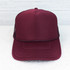 Maroon Foam Trucker Hat, front view of a maroon mesh trucker cap with foam front panel and curved brim set against a white wooden background.