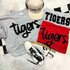 Tigers Fluffy Patch, close-up of a fluffy patch with the word 'tigers' in black on a gray background, applied to various apparel items and accessories.