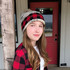 C.C. Buffalo Plaid Beanie, woman wearing a wool knit buffalo plaid beanie with mixed colors including red, black, and white, featuring a pom-pom on top.