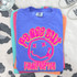 Peace Out Happy Face Grade DTF Heat Transfer, colorful graphic design with a smiling face and playful text on a blue T-shirt, displayed with folded shirts and shoes in the background.