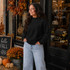 Blank Mockneck Sweatshirt — Preorder | Multiple Colors, black mockneck sweatshirt worn by a woman with autumn decorations outside a boutique store.