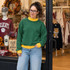 Blank Mockneck Sweatshirt — Preorder | Multiple Colors, woman wearing a green sweatshirt with yellow accents, casual style, in a retail clothing store.