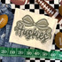 Camo Bow School Mascot DTF Heat Transfer, camouflage bow design with the word 'Huskies' in stylized lettering on a fabric, surrounded by football-themed items.