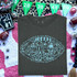 Football Doodle CHOOSE YOUR COLOR DTF Heat Transfer, a gray T-shirt featuring a football-themed doodle design with sports equipment and phrases, surrounded by decorations like footballs and a party banner.