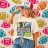 Retro Mascot Collage DTF Heat Transfer, colorful and playful football-themed design on a t-shirt with a smiling woman wearing a cap that says 'Game Day' surrounded by footballs with smiley faces in the background.