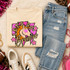 Pink Glitter Mascot - 62 teams - DTF Heat Transfer, a colorful cartoon of a bronco horse with text and stars on a beige t-shirt, paired with distressed blue jeans, sneakers, and accessories.