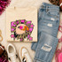 Pink Glitter Mascot - 62 teams - DTF Heat Transfer, featuring a colorful graphic of a pink glitter mascot eagle with stars and bold text on a beige sweatshirt, surrounded by casual clothing and accessories.