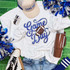 Game Day Sequin Patch With Football, football-themed sequin patch on a white t-shirt surrounded by sports accessories and cheering items.