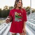 Touchdown Game Day Pennants DTF Heat Transfer, a woman wearing a red oversized t-shirt with football-themed graphic design, holding a football, in a sports stadium setting.