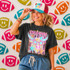 Neon Star Mascot DTF Transfers | School Spirit Mascot Collection, colorful neon star-shaped mascot design on a T-shirt and a woman wearing a cap with 'Game Day' text in a lively sports-inspired setting.