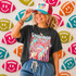 Neon Star Mascot DTF Transfers | School Spirit Mascot Collection, vibrant neon star-themed mascot design on a T-shirt worn by a smiling woman amidst a backdrop of colorful football-shaped decorations.