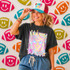 Neon Star Mascot DTF Transfers | School Spirit Mascot Collection, vibrant holographic lion mascot design with star glasses on a woman's black t-shirt, surrounded by colorful football-shaped smiley face decorations.