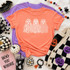 Patterned Trio Ghosts DTF Transfer, Halloween-themed T-shirt with floral, leopard, and polka dot ghost designs laid on a flat surface surrounded by Halloween decorations.