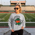 Dotted Mascot DTF Transfers | School Spirit Mascot Collection, young woman wearing a sweatshirt with a cartoon alligator mascot design standing on a football field.