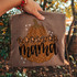 Blessed Mama Pumpkin DTF Transfer | Fall Mom Design, image of a fabric with a pumpkin graphic and the words 'Blessed Mama' surrounded by stars, held up outdoors with trees in the background.