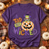 A Tad Bit Wicked Halloween DTF transfer with witch-hatted frog in a striped sweater and bow tie sitting on a checkered jack-o'-lantern pumpkin Shown on a Violet t-shirt.